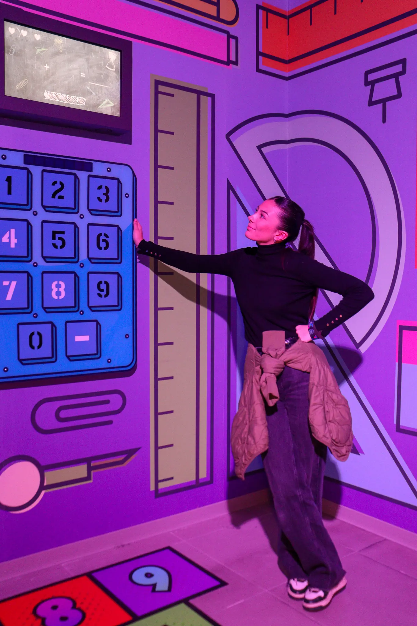 Joueuse dans une salle du Cube Challenge aux couleurs vives, devant un pavé numérique géant