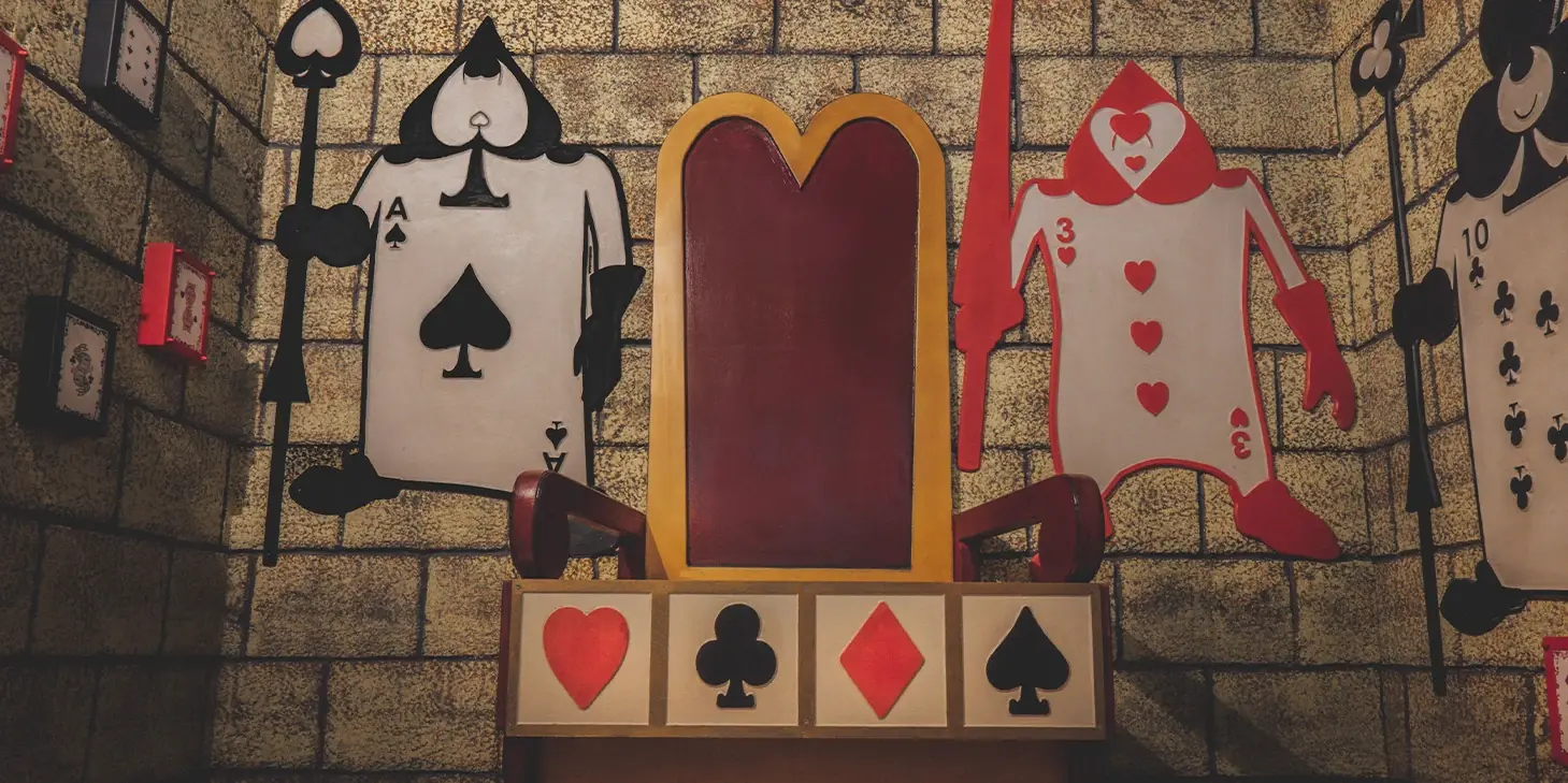 Salle Alice au Pays des Merveilles : trône rouge entouré de cartes à jouer géantes
